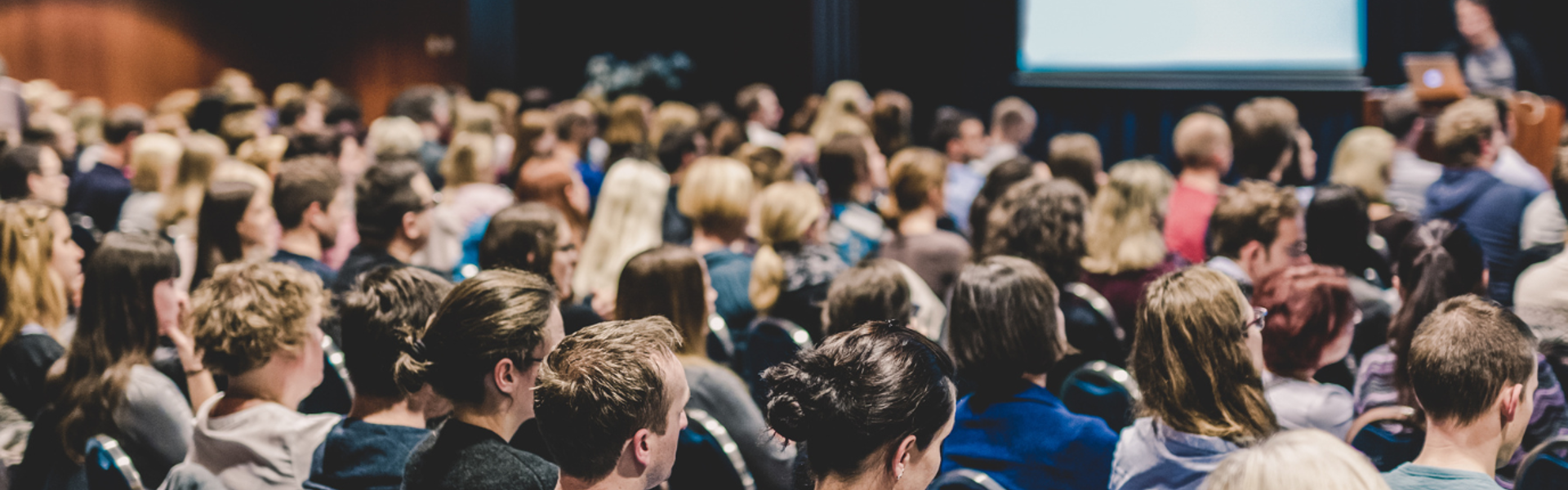 People at a conference sat in rows with a presenter at the front.