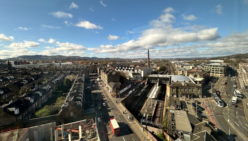 View of a railway station and residential and commercial buildings, with hills in the background.